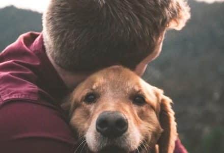 man cuddling dog